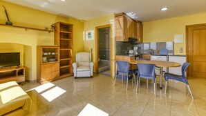 Un espace de vie compact comprenant un coin repas, une kitchenette et un téléviseur dans le salon.