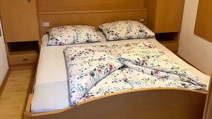 Ein Einzelbett mit Blumenmuster auf der Bettwäsche, einem Holzkopfende und eingebauten Stauraumschränken.
