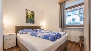Ein Schlafzimmer mit Bett, Nachttischen, einem Fenster mit Blick und einem Bild an der Wand.