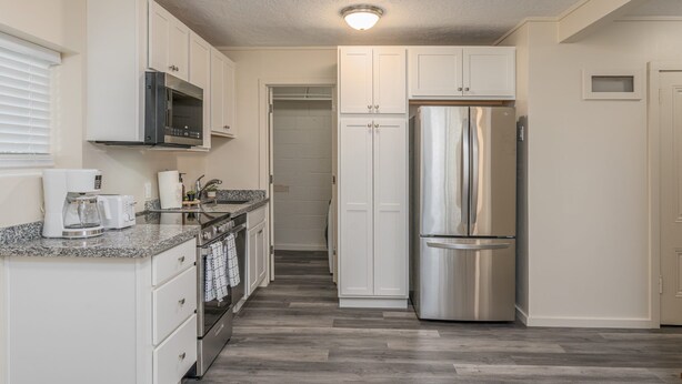 A modern kitchen with white cabinets, stainless steel appliances, and a granite countertop. - Cheerful 1-Bedroom with free parking (Reno)