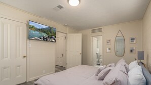 A bedroom with a bed, a TV mounted on the wall, and a door leading to another room. - Cheerful 1-Bedroom with free parking (Reno)