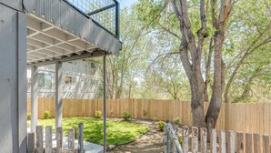 A backyard with a wooden fence, a tree, and a grassy area. - Cheerful 1-Bedroom with free parking (Reno)