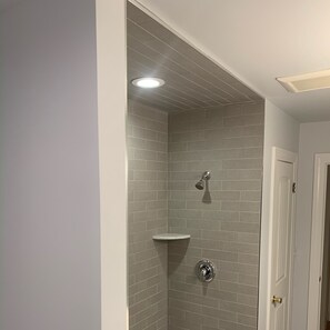 A shower with grey tiles, a white door, and a ceiling light. - Belmar House 2 blocks from beach (Belmar)