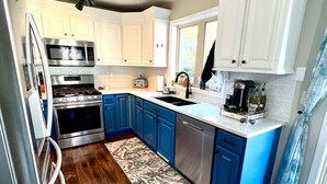 Una cocina moderna con electrodomésticos de acero inoxidable, armarios azules y piso de madera.