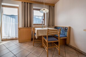 Un coin repas avec une table et des chaises, une fenêtre avec des rideaux et un luminaire suspendu.