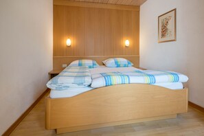 Un lit en bois avec une tête de lit, deux lampes fixées au mur et un tableau encadré accroché au mur.