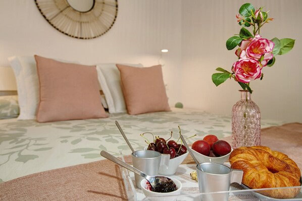 A neatly arranged breakfast table with a croissant, cherries, and a vase of flowers.