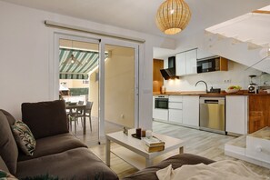 A modern living room with a sofa, a coffee table, and a kitchen in the background.