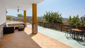 Un patio cubierto con mobiliario exterior, una cerca de madera y vistas a las colinas.