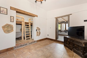 Una habitación con una escalera de madera, un televisor sobre un mueble de madera y una pared de piedra.