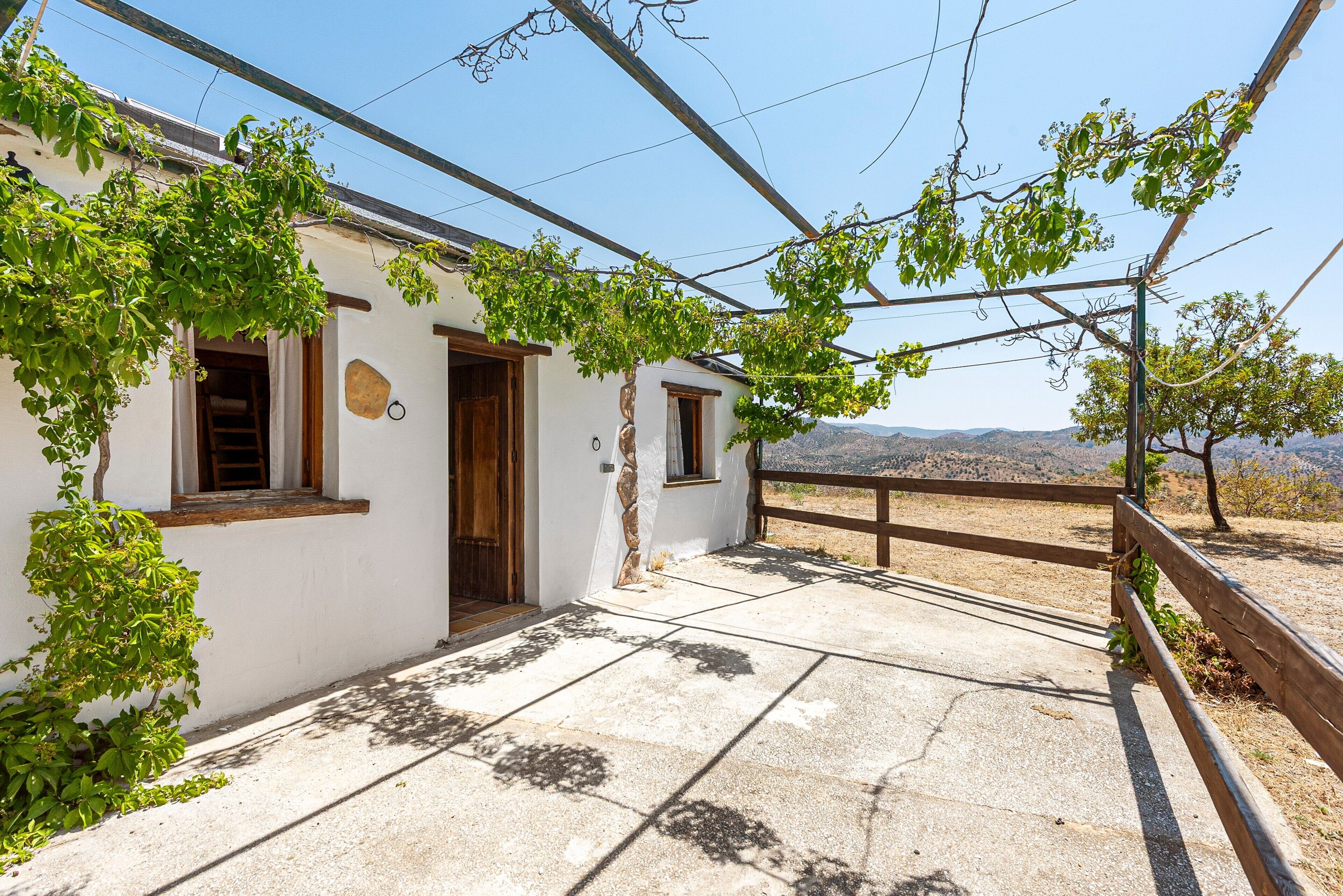 Un bâtiment blanc avec une porte en bois, une petite fenêtre et un mur en pierre.