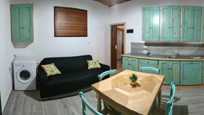 A compact living space with a sofa, a dining table, a washing machine, and teal cabinets. - Apartment 'Perla Marina' with Garden & Terrace (grosseto)