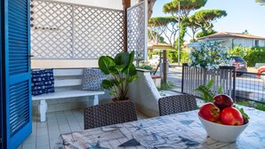 A patio with a table, chairs, a bench, and a bowl of fruit. - Apartment 'Perla Marina' with Garden & Terrace (grosseto)