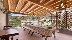 An outdoor patio with a wooden table and benches, a hanging light fixture, and a view of a hilly landscape. - Country House 'Quinta Do Silêncio T2' with Mountain View, Wi-Fi and Air Conditioning (Tavira)
