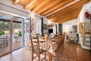 A dining area with a wooden ceiling, a table set for four, and a view of the outdoors.