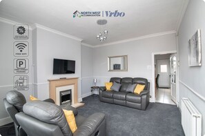 A modern living room with a fireplace, leather sofas, and a flat-screen TV. - Bolton 2 Bedroom House | Free Parking & WiFi | Ideal for Long Stays (Tonge Fold)