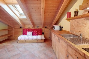 Habitación compacta con cama, kitchenette y tragaluz.