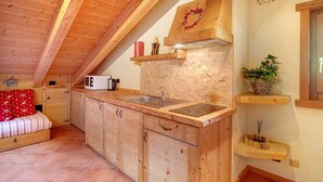 Une cuisine de taille réduite, avec des meubles de rangement en bois, un évier et un four à micro-ondes.