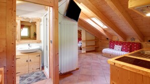 Un intérieur en bois comprenant une salle de bain, un téléviseur, un radiateur et un canapé.