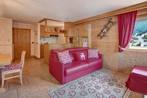 A wooden interior with a red sofa, a dining table, and a kitchen area.