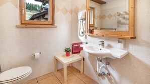 Ein Badezimmer mit Toilette, Waschbecken, Spiegel und einem kleinen Tisch mit einer Pflanze.