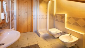 Een badkamer met douche, toilet, bidet en wastafel.