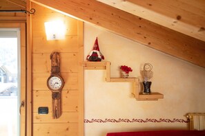 A wooden interior with a wall-mounted clock, a gnome figurine, and a small shelf with decorative items.