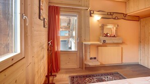 Een houten interieur met een bed, een raam, een radiator en een spiegel.