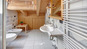 Ein Badezimmer aus Holz mit zwei Waschbecken, einer Toilette und einem kleinen Tisch mit einer Pflanze.