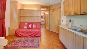 Una habitación compacta con una cama, un pequeño espacio kitchenette y un baño al fondo.
