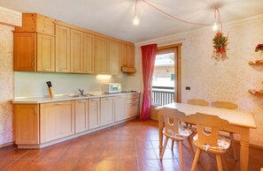 Una cocina con armarios de madera, microondas y una mesa de comedor con sillas.