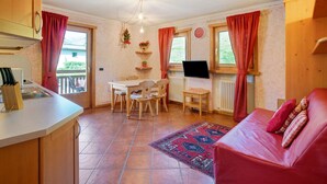 Una cocina compacta con comedor, un sofá rojo y un televisor.