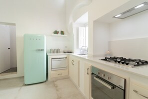 Une cuisine moderne avec des meubles blancs, un réfrigérateur de couleur turquoise, une cuisinière à gaz et un four encastré.