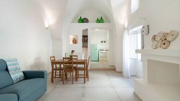Un interior moderno con comedor, sofá y cocina al fondo.
