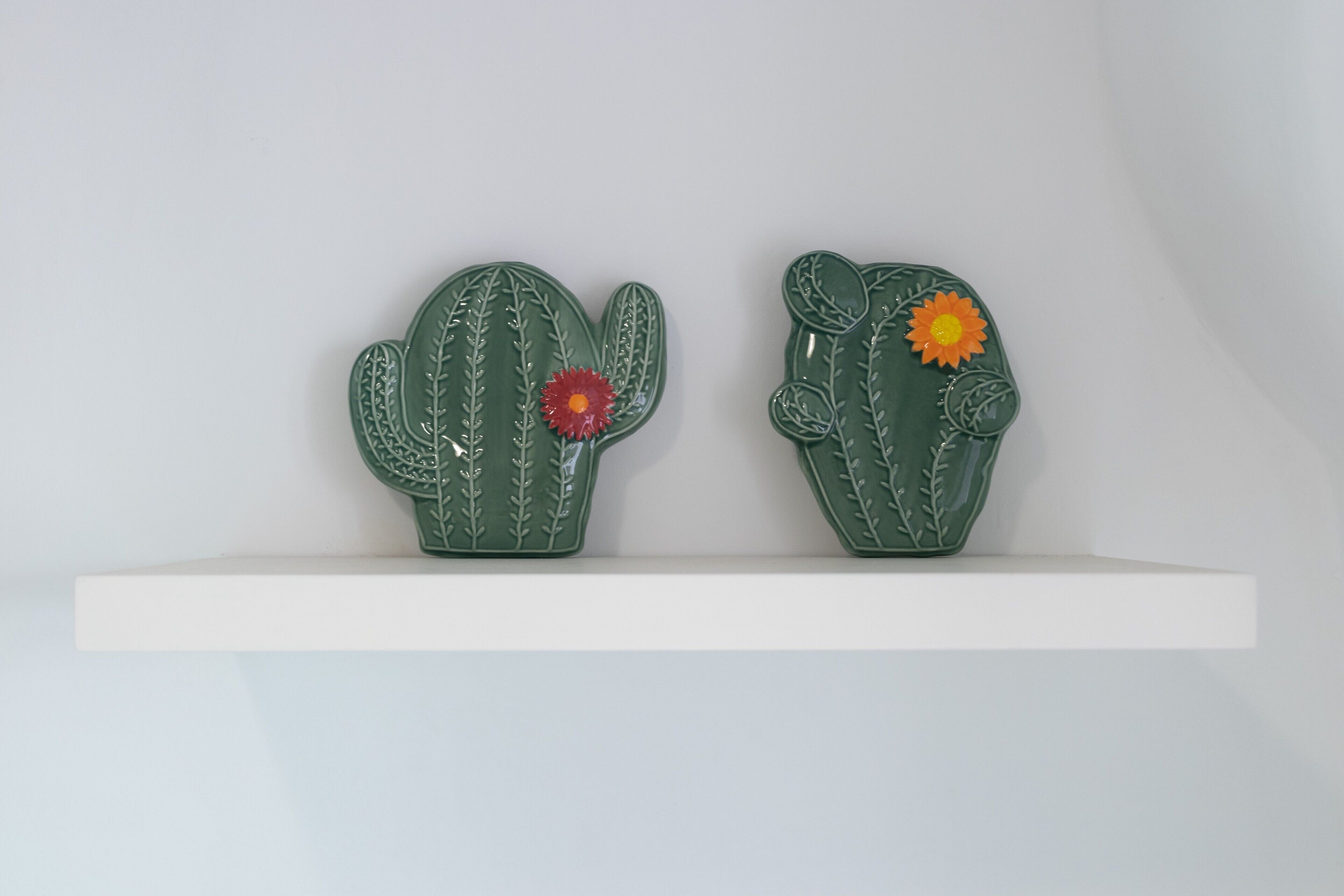 Two green cactus-shaped objects on a white shelf.