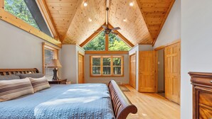 Un dormitorio con una cama grande, techo de madera y tragaluz.