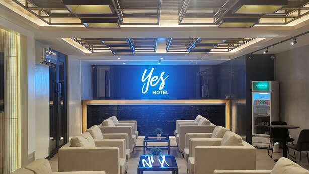 A modern hotel lobby with a reception desk, seating area, and a vending machine.