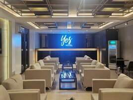 Un moderno vestíbulo de hotel con recepción, zona de estar y máquina expendedora.