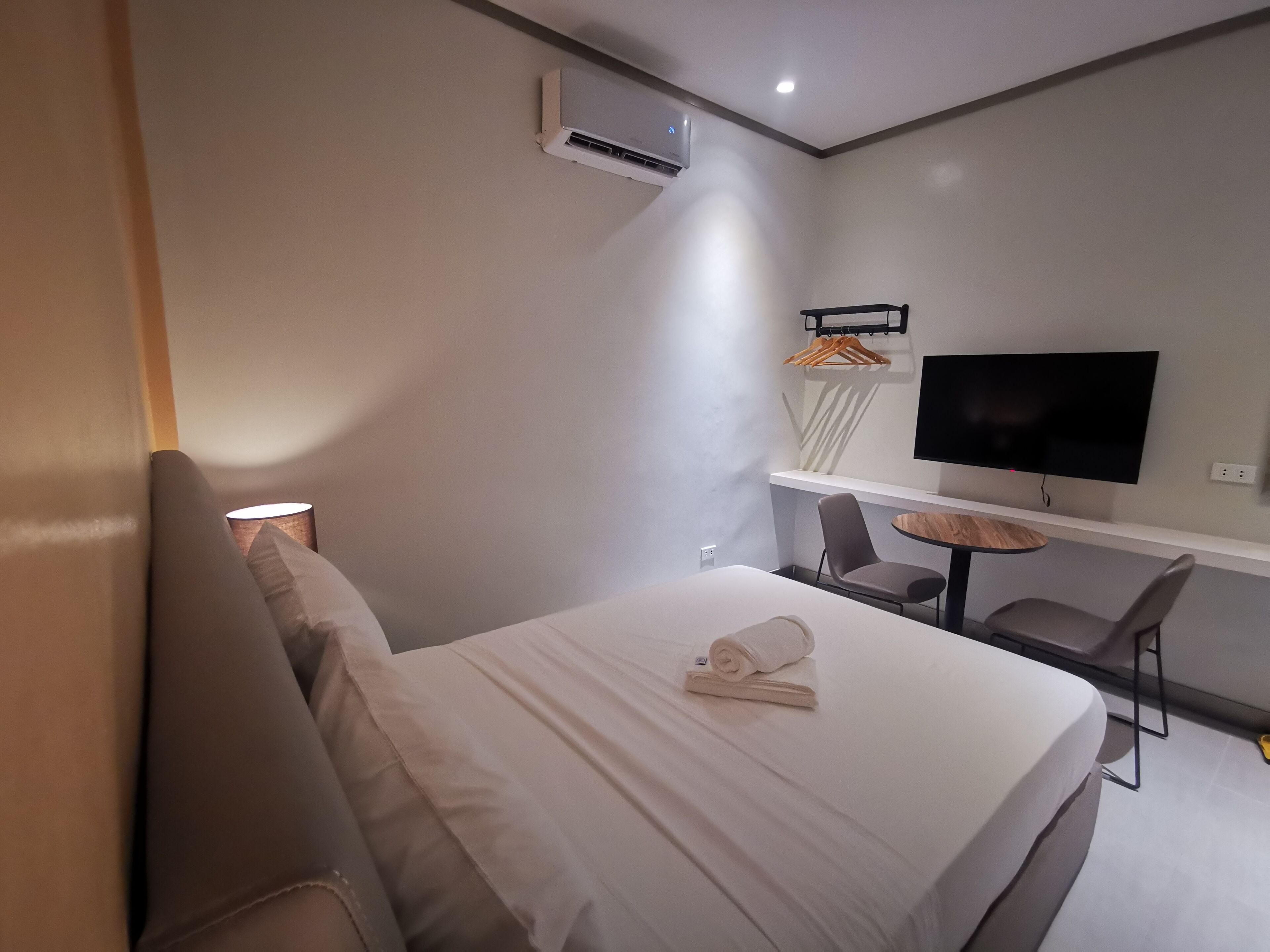 Une chambre d’hôtel moderne équipée d’un lit, d’un bureau, d’une chaise, d’une télévision et d’un appareil de climatisation.