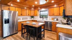 Una cocina moderna con armarios de madera, electrodomésticos de acero inoxidable y una isla central con taburetes.