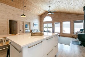 A modern kitchen with a large island, wooden ceiling, and large windows offering views of a snowy landscape. - Heaven on Earth (Tobermory)