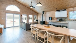 En mysig stuga med en matplats, ett kök och stora fönster som erbjuder utsikt över det snötäckta landskapet.