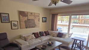 A living room with a sectional sofa, a coffee table, and a ceiling fan.