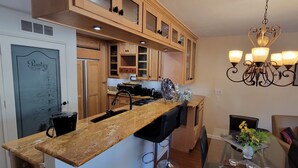 A kitchen with wooden cabinets, a granite countertop, a built-in stove, and a chandelier.