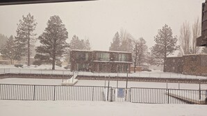 A view of a building with a snow-covered roof and a fenced area in front.