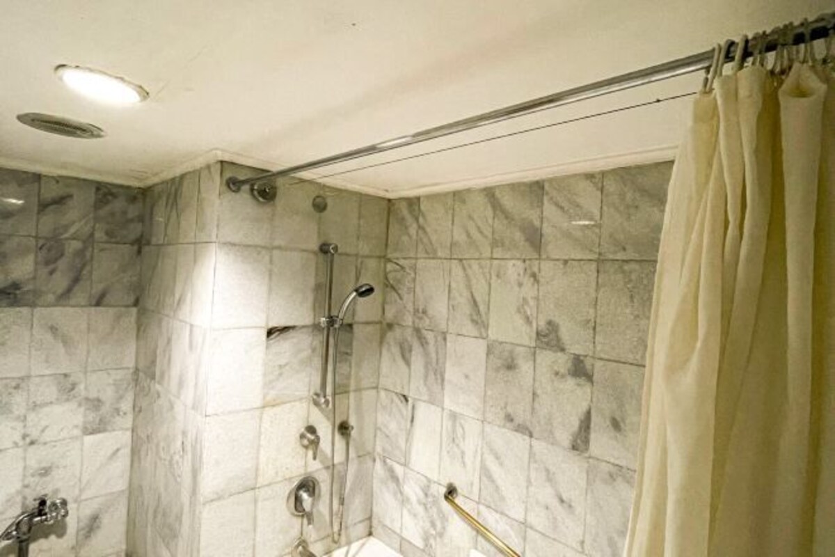 A bathroom with a shower, marble tiles, and a curtain.