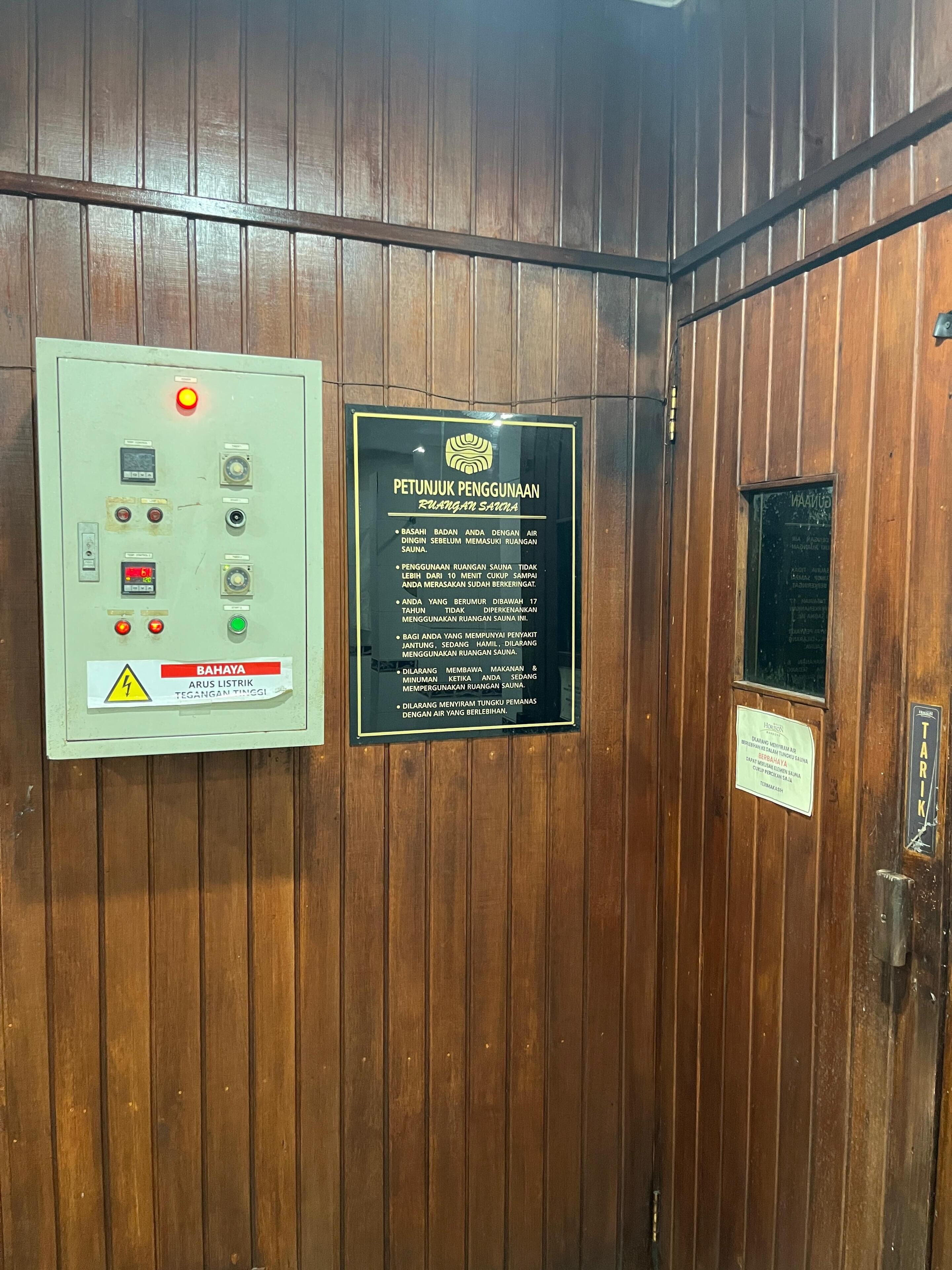 An elevator interior with a control panel, a safety warning sign, and informational signs.
