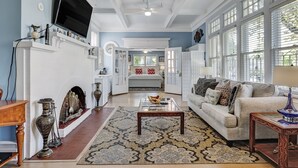 A spacious living room with a fireplace, a television mounted on the wall, and a large window providing natural light. - Walk Everywhere in Starland, Heated Pool Access (Savannah)