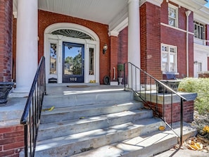 Step up to the entrance of this charming building, featuring a blue door and white columns.