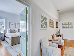 Une chambre à coucher moderne avec un lit, une chaise et une petite table. Des tableaux encadrés ornent le mur.